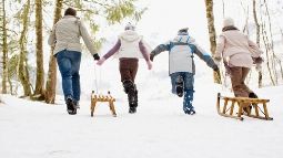 Family pulling sleds through snow